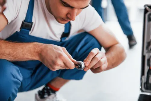 Young male mover in blue uniform works indoors in the room - Alpha Packers and movers